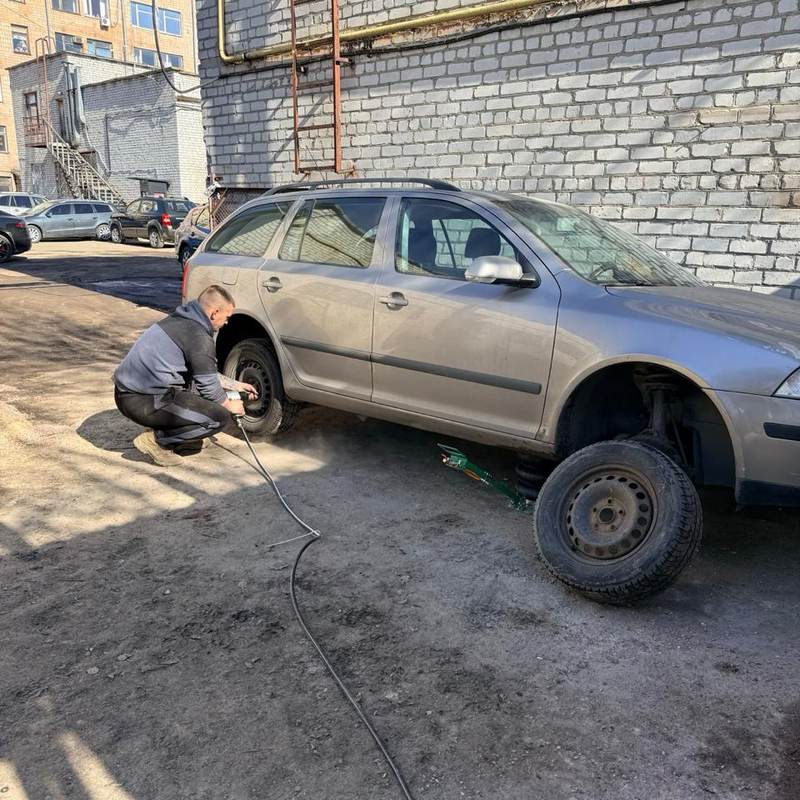 Майстер знімає колесо з авто на домкраті